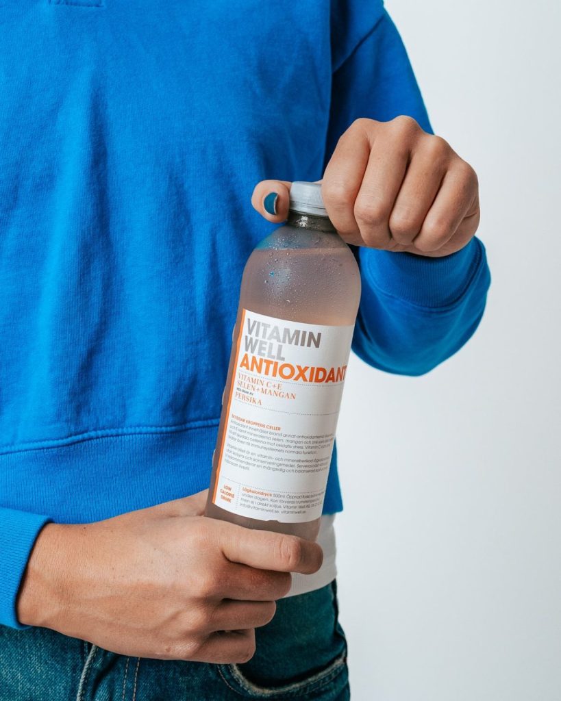 Човек отваря бутилка Vitamin Well Antioxidant